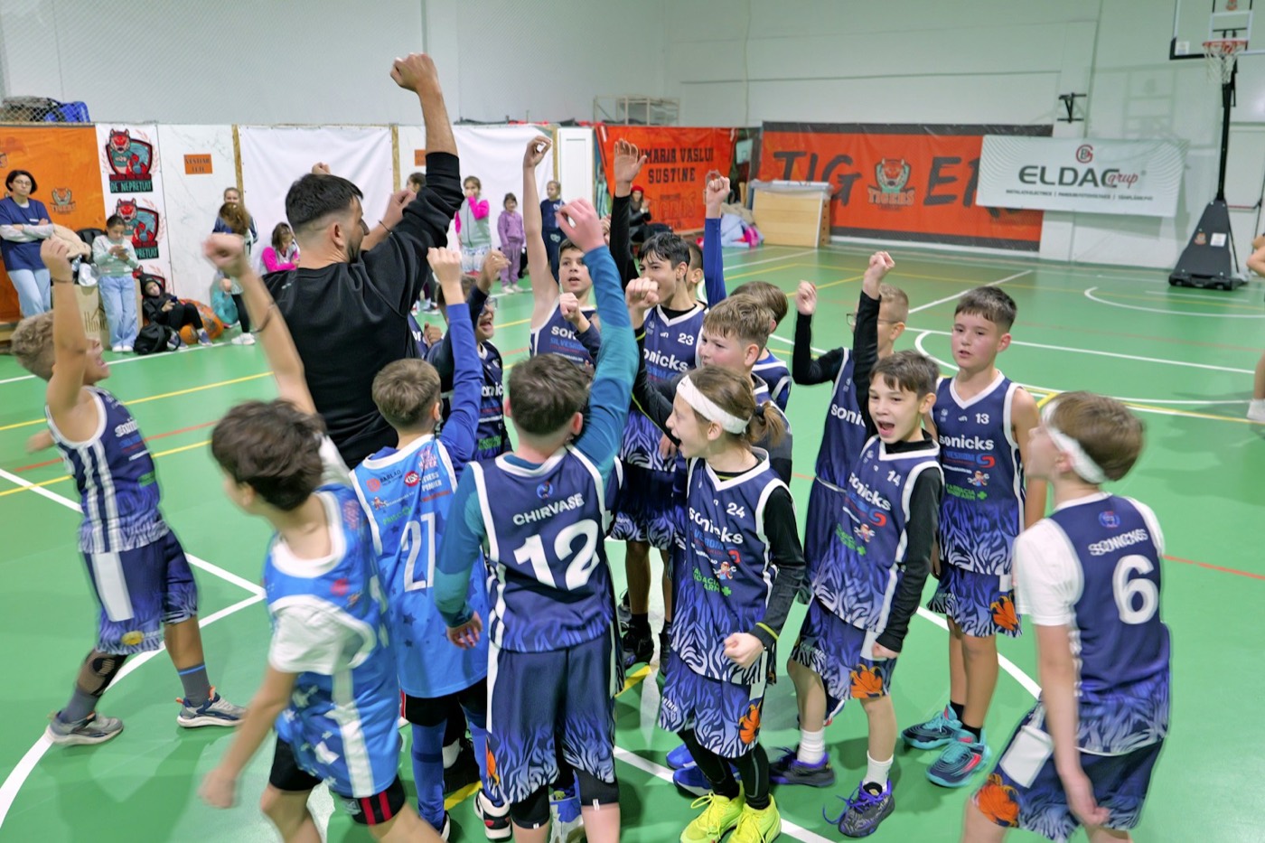 A children’s basketball team celebrating a win with their coach